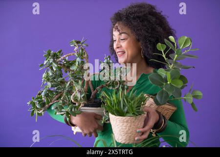 Ritratto in studio di una donna sorridente che tiene le piante in vaso Foto Stock
