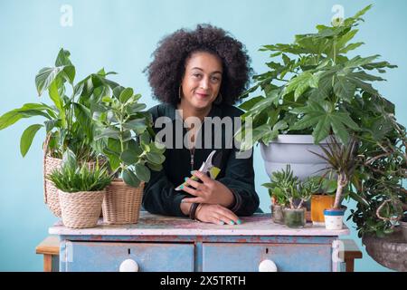 Ritratto in studio di una donna sorridente con piante in vaso Foto Stock