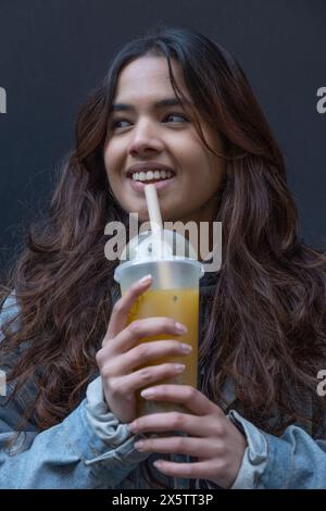 Ritratto di una giovane donna allegra che beve il tè bollicine Foto Stock