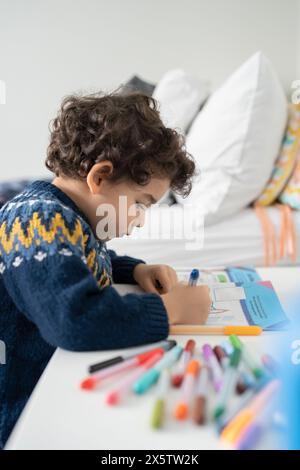 Ragazzo (2-3) colorare in un libro da colorare a casa Foto Stock