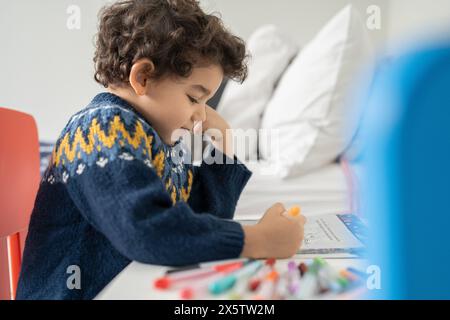 Ragazzo (2-3) colorare in un libro da colorare a casa Foto Stock