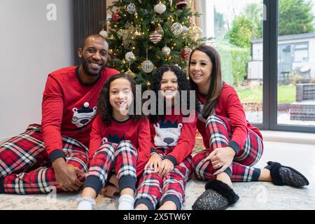 Ritratto di genitori sorridenti con due figlie davanti all'albero di Natale Foto Stock