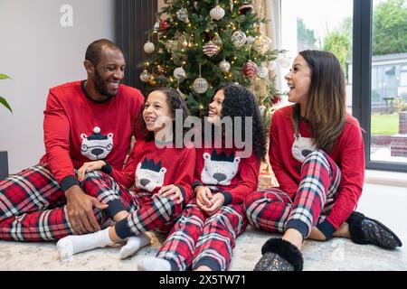 Ritratto di genitori sorridenti con due figlie davanti all'albero di Natale Foto Stock