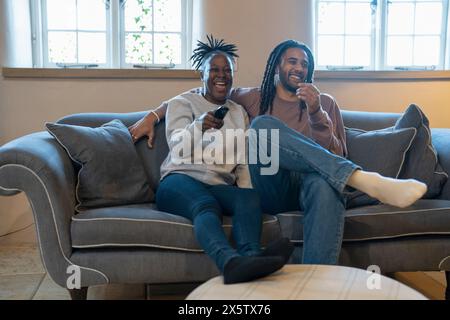 Una coppia felice seduto sul divano nell'accogliente soggiorno e guardando la TV Foto Stock