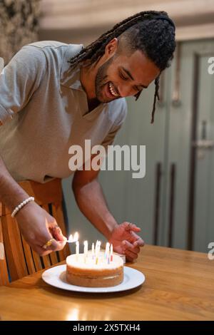 Uomo che accende le candele sulla torta di compleanno Foto Stock