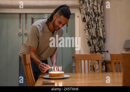 Uomo che accende le candele sulla torta di compleanno Foto Stock