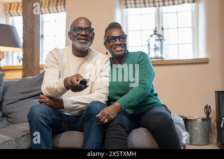 Una coppia di anziani sorridente che guarda la TV Foto Stock