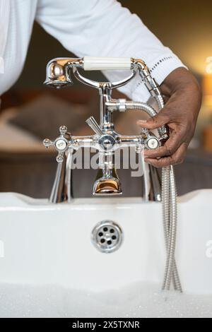 Mani di una donna anziana che fa il bagno di bolle Foto Stock