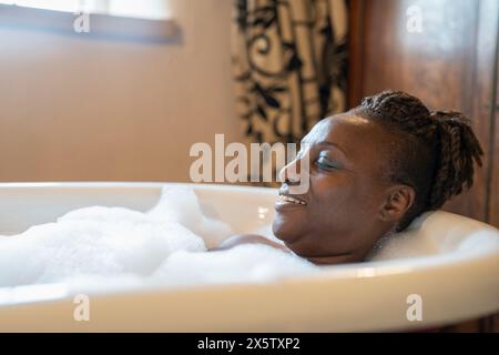 Donna anziana che fa un bagno di bolle Foto Stock
