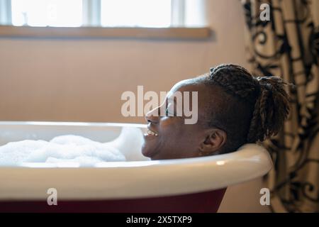 Donna anziana che fa un bagno di bolle Foto Stock