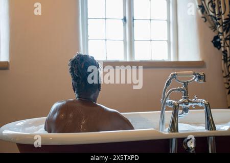 Donna anziana che fa un bagno di bolle Foto Stock
