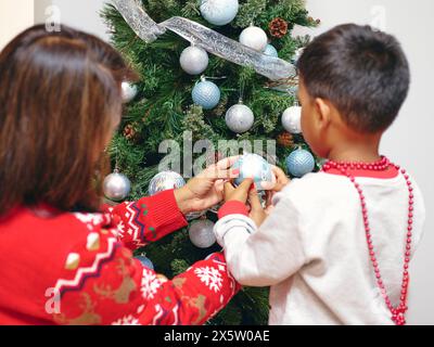 Madre e figlio decorare albero di Natale Foto Stock