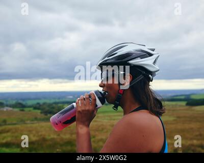 Ciclista donna che beve dalla bottiglia d'acqua Foto Stock