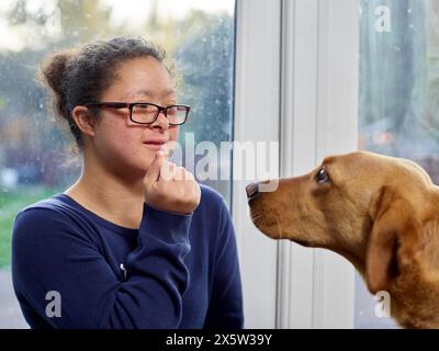 Ragazza con la sindrome di Down che gioca con il cane a casa Foto Stock