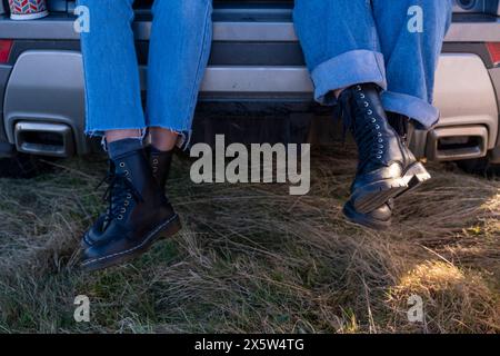 Donna con piedi in stivali di pelle che pendono dall'auto Foto Stock