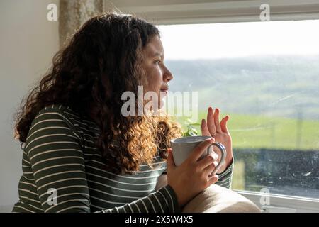 Giovane donna che sventola dalla finestra Foto Stock