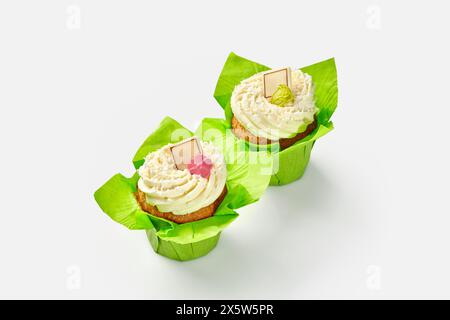 Due cupcake con panna montata in involucri di carta verde Foto Stock