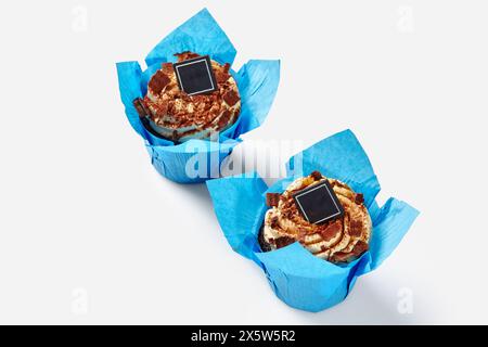 Cupcake al cioccolato con panna montata in involucri di carta blu Foto Stock