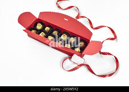 Squisite caramelle al cioccolato in confezione regalo rossa con nastro tratteggiato Foto Stock