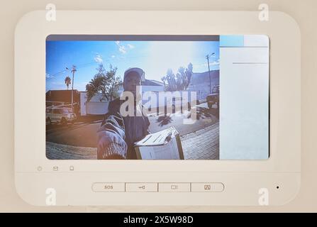 Consegna, telecamera di sicurezza e casa intelligente con corriere uomo sullo schermo per e-commerce, distribuzione o spedizione. Display, campanello o catena di approvvigionamento Foto Stock