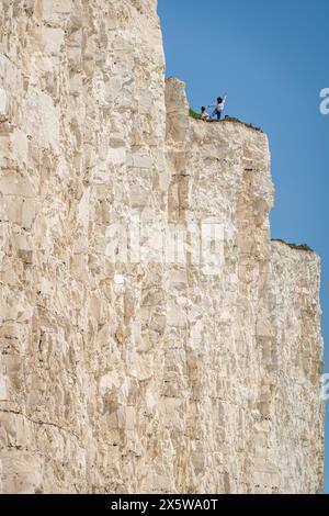 Beachy Head, East Sussex, Regno Unito. 11 maggio 2024. La gente posa per le foto pericolosamente vicino al bordo della scogliera che si sgretola sulla costa, poiché si prevede che la temperatura raggiunga i 27 °C oggi nel fine settimana più caldo dell'anno finora. Beachy Head, East Sussex, UK Credit: Reppans/Alamy Live News Foto Stock