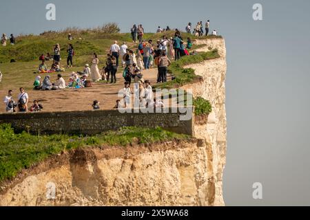 Beachy Head, East Sussex, Regno Unito. 11 maggio 2024. Le persone si siedono precariamente vicino alla scogliera che si sgretola sulla costa, poiché si prevede che la temperatura raggiunga i 27 °C oggi nel weekend più caldo dell'anno finora. Beachy Head, East Sussex, UK Credit: Reppans/Alamy Live News Foto Stock