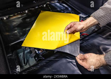 Addetto all'assistenza automatica che installa materiale in schiuma insonorizzante sul rivestimento interno della porta dell'auto, sintonizza il suono dell'auto o installa l'isolamento acustico. Processo di c Foto Stock