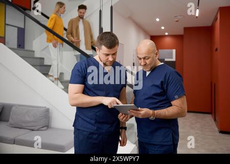 Medici professionisti discutono insieme i rapporti medici dei pazienti nella sala clinica Foto Stock