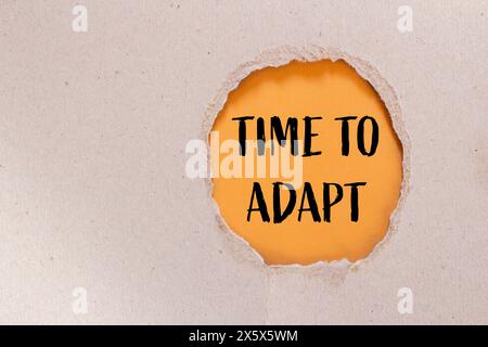 Tempo di adattamento scritto su carta strappata con sfondo arancione. Tempo concettuale per adattare il simbolo. Copia spazio. Foto Stock