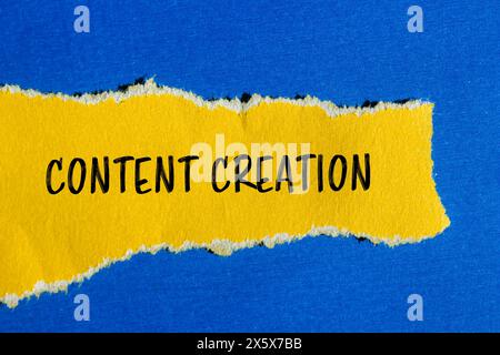 Parole per la creazione di contenuti scritte su carta gialla strappata con sfondo blu. Simbolo di creazione di contenuti concettuali. Copia spazio. Foto Stock