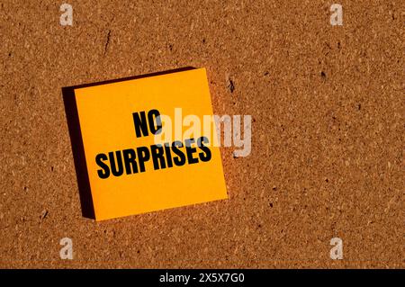 Nessuna sorpresa parole scritte su un adesivo di carta arancione con sfondo marrone. Simbolo concettuale di nessuna sorpresa. Copia spazio. Foto Stock