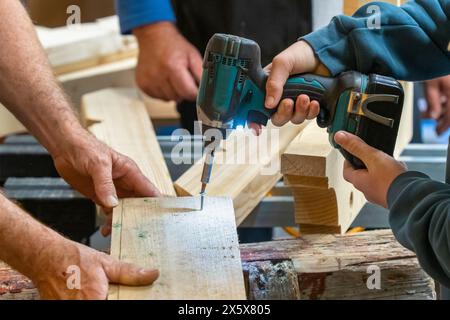Inserire le viti in una scheda con un cacciavite elettrico in un'officina di carpenteria Foto Stock