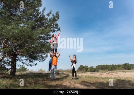 Una donna sta sulle spalle di un uomo. Una donna con un braccio teso che cerca di catturare una rete cellulare. Foto Stock