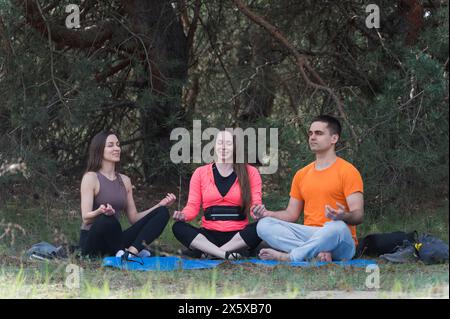 Tre amici meditano seduti nella posizione del loto mentre camminano. Foto Stock