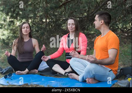 Tre amici meditano seduti nella posizione del loto mentre camminano. Foto Stock