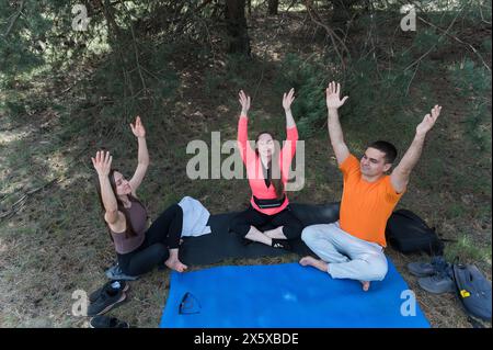 Tre amici meditano seduti nella posizione del loto mentre camminano. Foto Stock