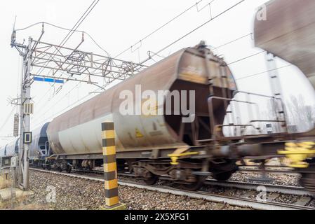 Passaggio del treno merci in una nebbiosa giornata invernale. Sfocatura del movimento. Foto Stock