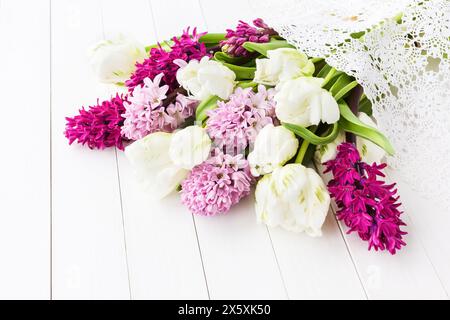 Tulipani bianchi e giacinti rosa su un tavolo di legno bianco. Sfondo delle vacanze, copia spazio Foto Stock