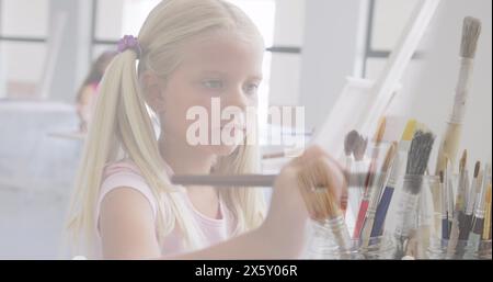 Immagine di pennelli di pittura su scolaretta caucasica che dipinge in classe d'arte Foto Stock