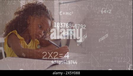 Immagine dei calcoli matematici e dei dati di una studentessa birazziale che si concentra sulla scrivania in classe Foto Stock