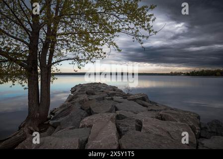 Sereno tramonto sul lago: Una vista maestosa sotto i cieli tempestosi Foto Stock