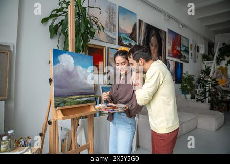 Pittori sorridenti coniugi lavorano sulla pittura. Artista donna felice con marito a casa studio laboratorio Foto Stock