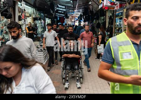 Onur cammina con suo fratello Mahsun Kaba nello storico bazar coperto di Hatay. Onur Kaba è un giovane di 22 anni di Hatay, una città più colpita dai terremoti di magnitudo 7,7 e 7,6 che hanno colpito Kahramanmara? Il 6 febbraio 2023. Onur è stato catturato in casa sua ed è rimasto intrappolato sotto le macerie per 87 ore. Dopo essere stato salvato, Onur è stato portato per la prima volta in un ospedale vicino, dove le sue gambe sono state curate per 12 giorni con vari trattamenti per prevenire l'amputazione. Alla fine, ha perso entrambe le gambe e continua la sua vita come amputato. Onur, che vive ancora ad Hatay, disse: "Ho passato molto d Foto Stock