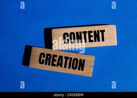 Parole per la creazione di contenuti scritte su blocchi di legno con sfondo blu. Simbolo di creazione di contenuti concettuali. Copia spazio. Foto Stock