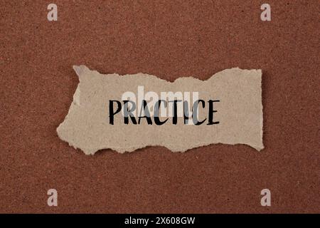 Esercitazione scritta su un pezzo di carta strappato con sfondo marrone. Simbolo della pratica concettuale. Copia spazio. Foto Stock