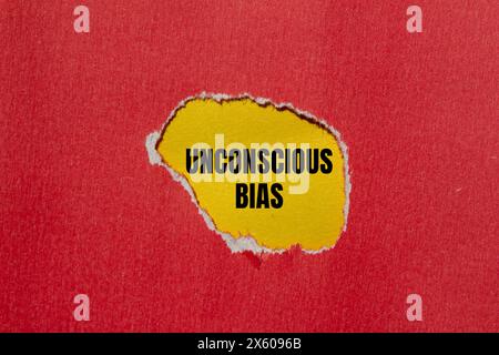 Parole di pregiudizio inconscio scritte su carta rossa strappata con sfondo giallo. Simbolo di pregiudizio inconscio concettuale. Copia spazio. Foto Stock