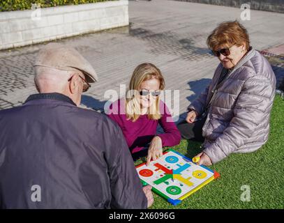 una famiglia che gioca un ludo insieme fuori. Anziani attivi Foto Stock