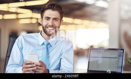 Computer portatile, cellulare e ritratto di un uomo d'affari in ufficio con un sorriso per scrivere e-mail aziendali online per la comunicazione. Felice, tecnologia e uomo Foto Stock