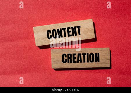 Parole per la creazione di contenuti scritte su blocchi di legno con sfondo rosso. Simbolo di creazione di contenuti concettuali. Copia spazio. Foto Stock