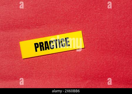 Esercitazione scritta su un adesivo di carta giallo con sfondo rosso. Simbolo della pratica concettuale. Copia spazio. Foto Stock